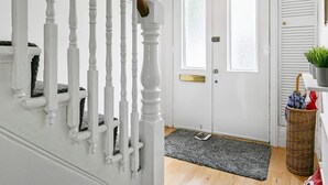 A staircase with white balusters and a wooden handrail, leading to a set of double doors with frosted glass panels and a brass handle. - Elegant GetAway House in Vibrant Clapham Juction - Pass the Keys (London)