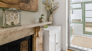 A room with a fireplace, a marble mantle, a vase with flowers, and a large painting on the wall. - Elegant GetAway House in Vibrant Clapham Juction - Pass the Keys (London)