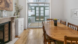 A dining room with a large wooden table, chairs, a fireplace, and a large window with a view of the outside. - Elegant GetAway House in Vibrant Clapham Juction - Pass the Keys (London)