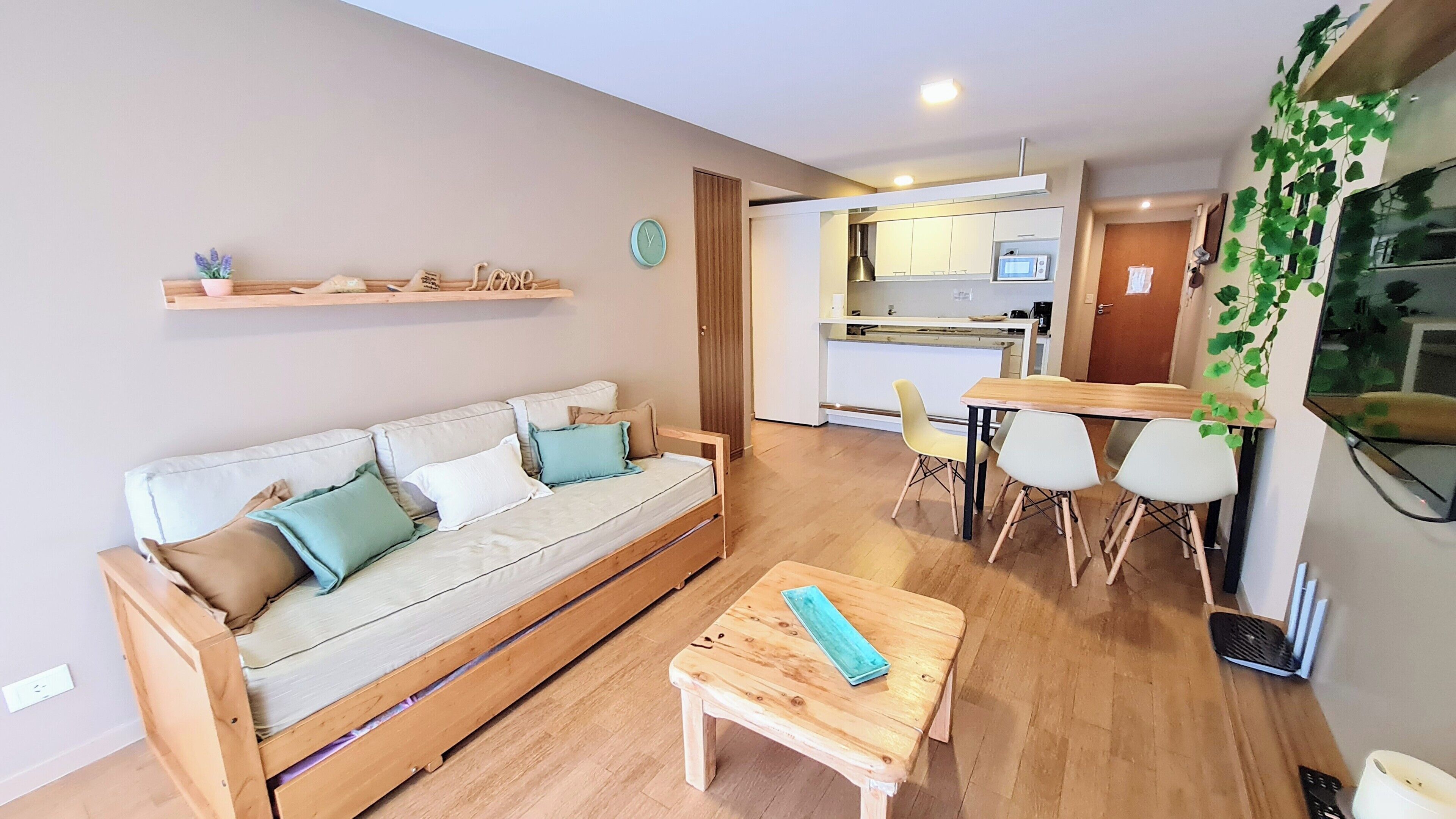 A modern living room with a sofa, a wooden coffee table, and a dining area with chairs.