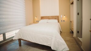 A bedroom with a bed, bedside lamps, a window with blinds, and a door. - Hotel Asiri  (Tarija)