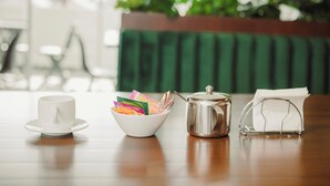 A table with a white cup, a bowl of colorful items, a metal pot, and a tissue box. - Hotel Asiri  (Tarija)