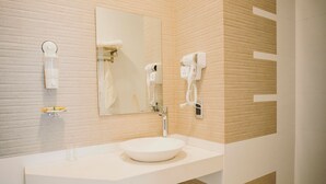A modern bathroom with a white sink, a large mirror, and a hairdryer mounted on the wall. - Hotel Asiri  (Tarija)