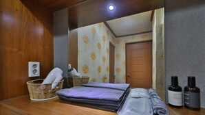 A bathroom with a wooden vanity, a mirror, a basket with towels, and toiletries. - Thema Motel (Sacheon)