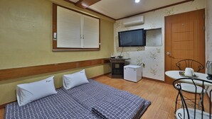 A hotel room with a bed, a small table with chairs, a television, an air conditioning unit, and a wooden door. - Thema Motel (Sacheon)