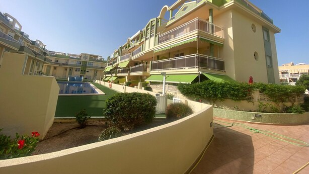 Un immeuble résidentiel à plusieurs étages, doté de balcons, d’une piscine et d’un jardin aménagé.