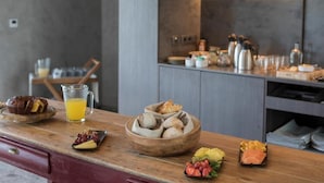 Een moderne keuken met een houten aanrecht waarop ontbijtartikelen staan, zoals muffins, een glas sinaasappelsap en een schaal fruit.