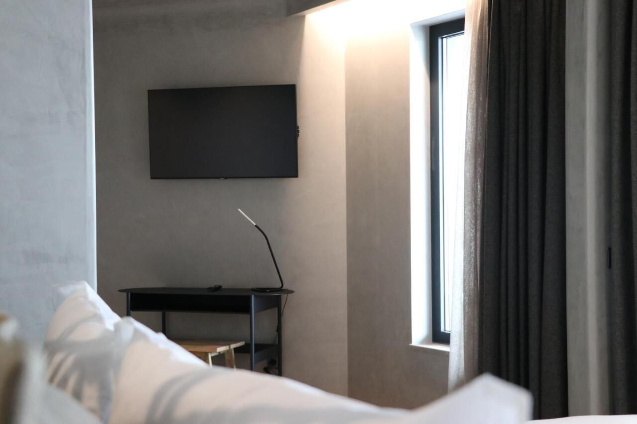 Una habitación de hotel con una cama, un escritorio y un televisor montado en la pared.