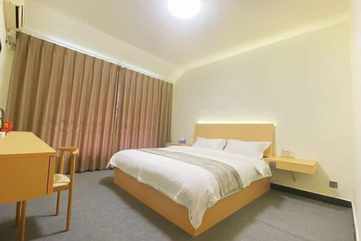 Une chambre d’hôtel avec un lit, un bureau, une chaise et une table de chevet.