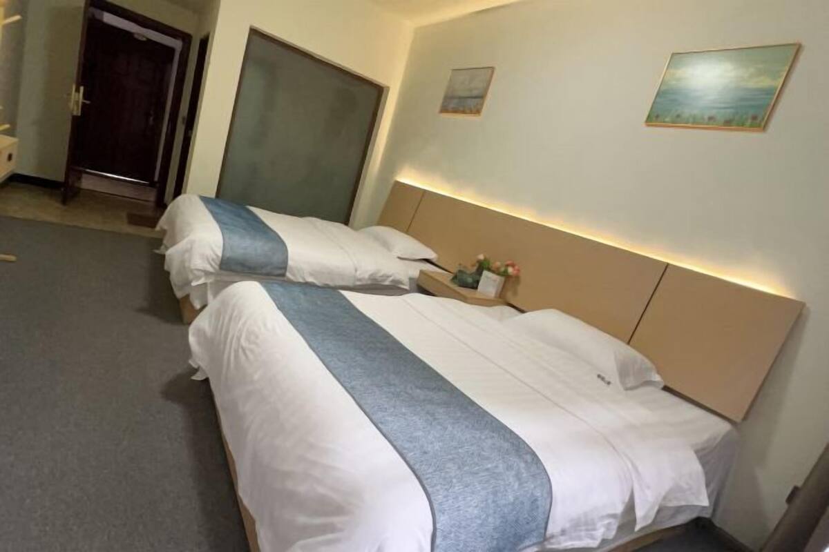Une chambre d’hôtel avec un lit, une table de chevet, des œuvres d’art murales et une porte.