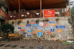 A wall with multiple signs in various languages, a bench, and a red banner. - fengchaominsu (Emeishan City)