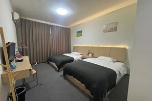 A hotel room with two beds, a desk, a chair, a small table, and a wall-mounted air conditioner. - fengchaominsu (Emeishan City)