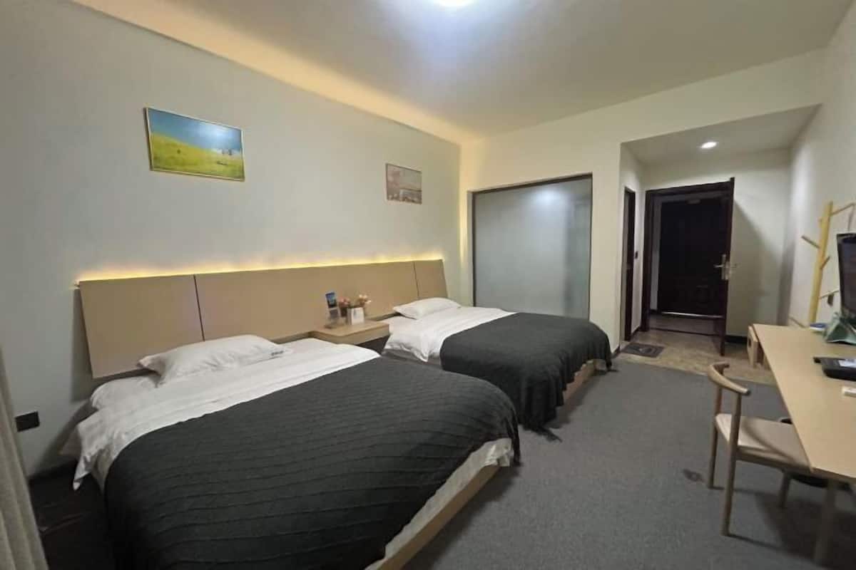 Une chambre d’hôtel avec deux lits, un bureau et une chaise.