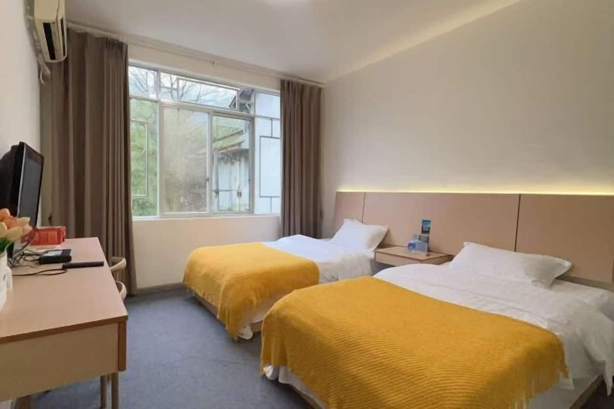 Une chambre d’hôtel avec deux lits, un bureau, une télévision et une fenêtre avec des rideaux.