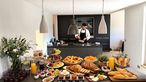 A breakfast buffet with various fruits, pastries, and beverages.