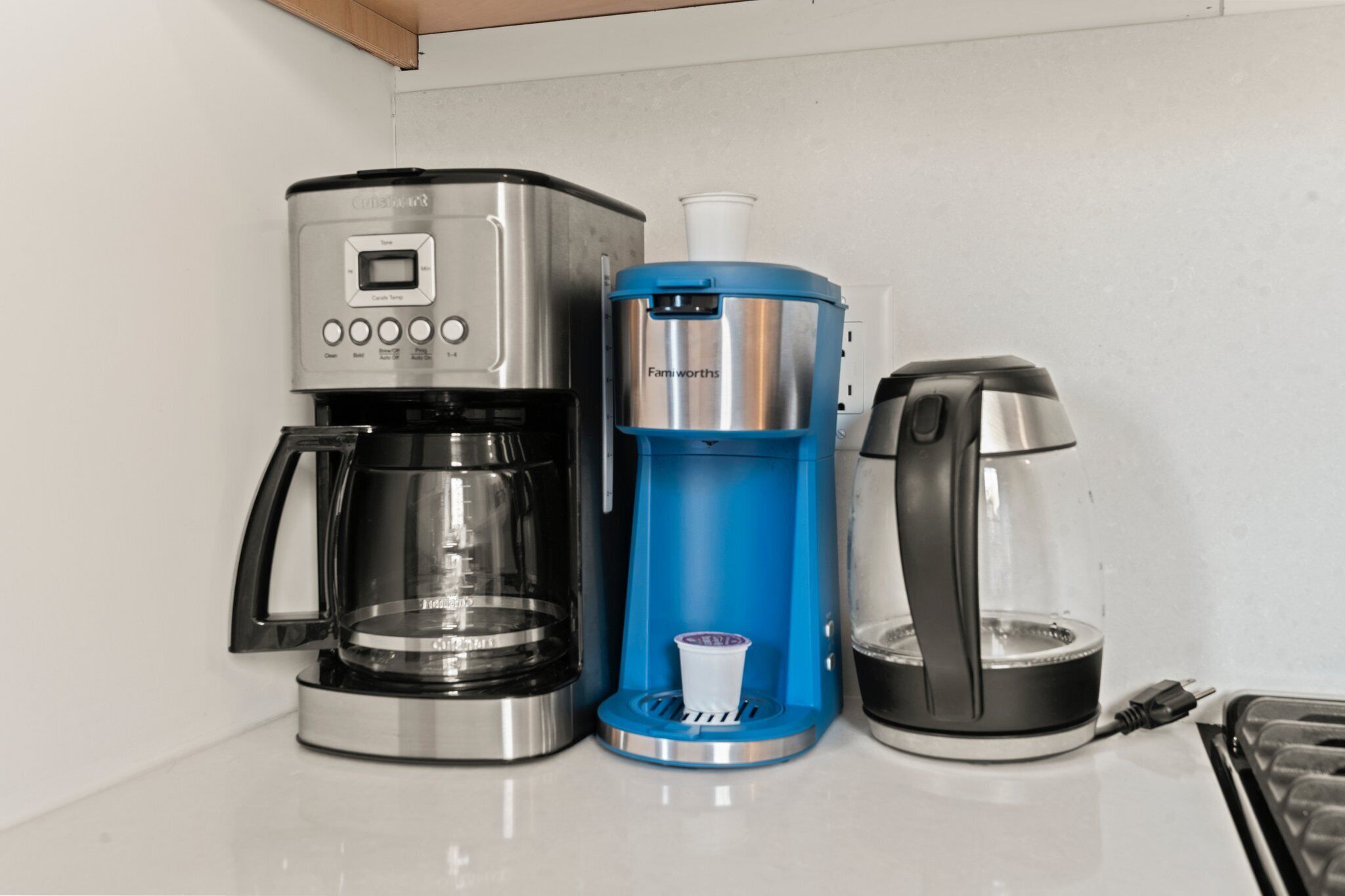 Una cafetera, un dispensador de agua y un hervidor de té sobre una encimera.