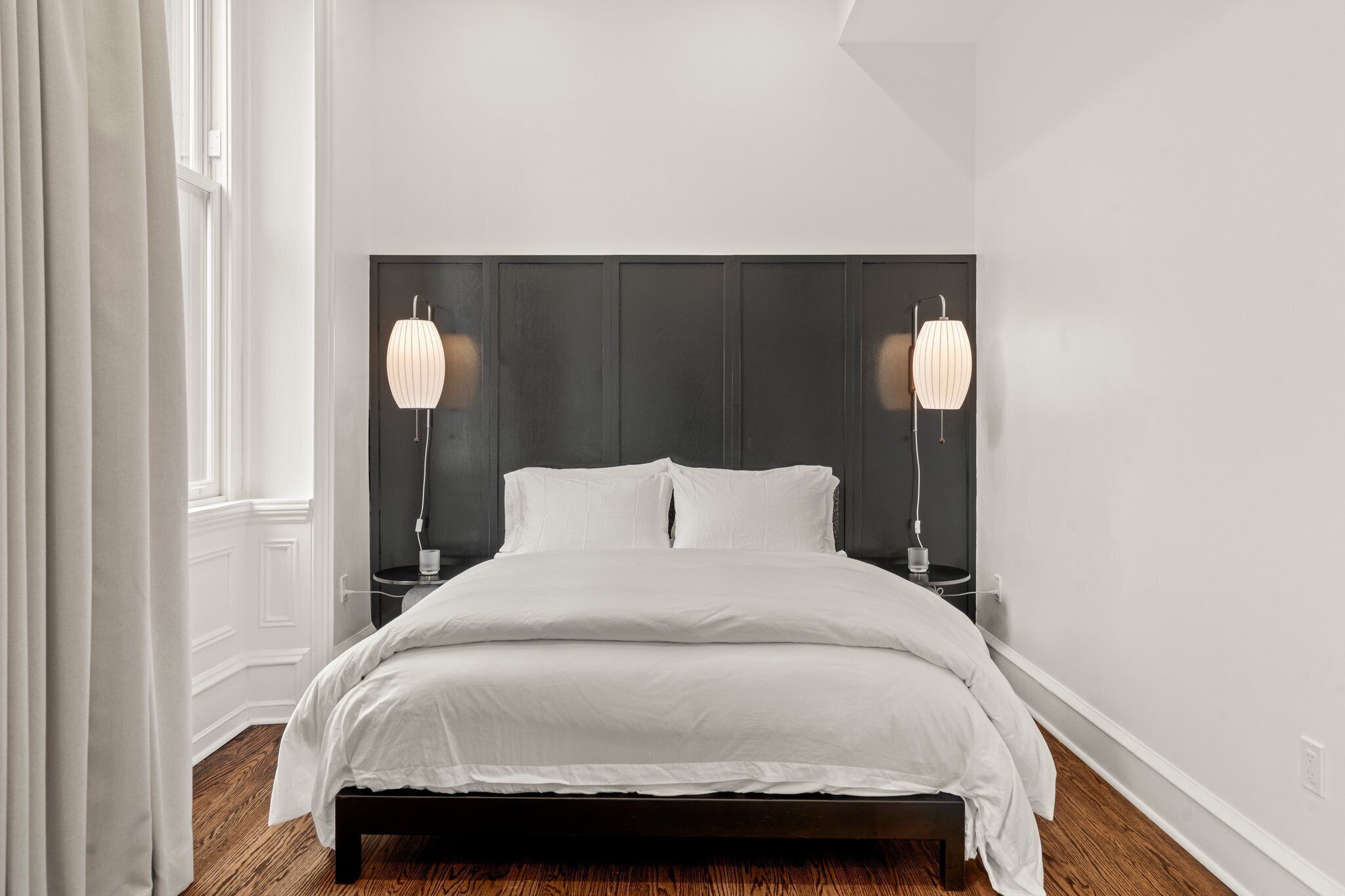 Una camera da letto moderna con un letto grande, una testata del letto scura e lampade ai comodini.
