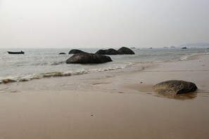 Ein Strand mit großen Felsen und ruhigem Wasser.