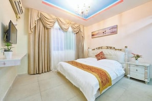 A bedroom with a bed, curtains, a painting, a nightstand, and a potted plant. - Xiamen Liangye Hotel (Xiamen)