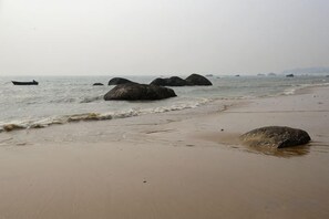 Uma praia com rochas grandes e águas calmas.