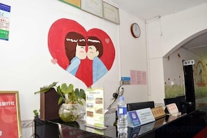 Una recepción con una obra de arte con forma de corazón, un reloj y una planta.