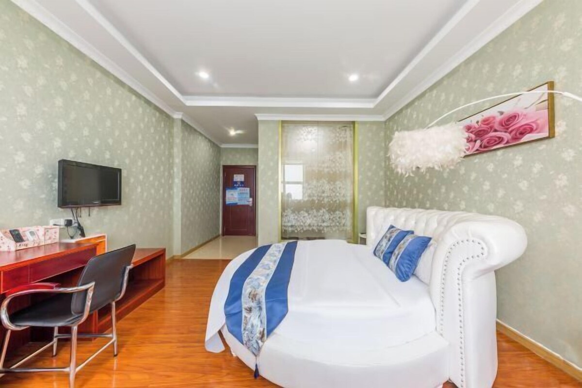 Ein Hotelzimmer mit einem Bett, einem Schreibtisch mit Stühlen, einem Fernseher und einer Wanddekoration.