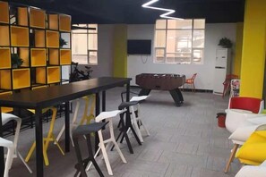 A room with a long table, chairs, a foosball table, and a bookshelf. - Junrun Hotel (Guangzhou)
