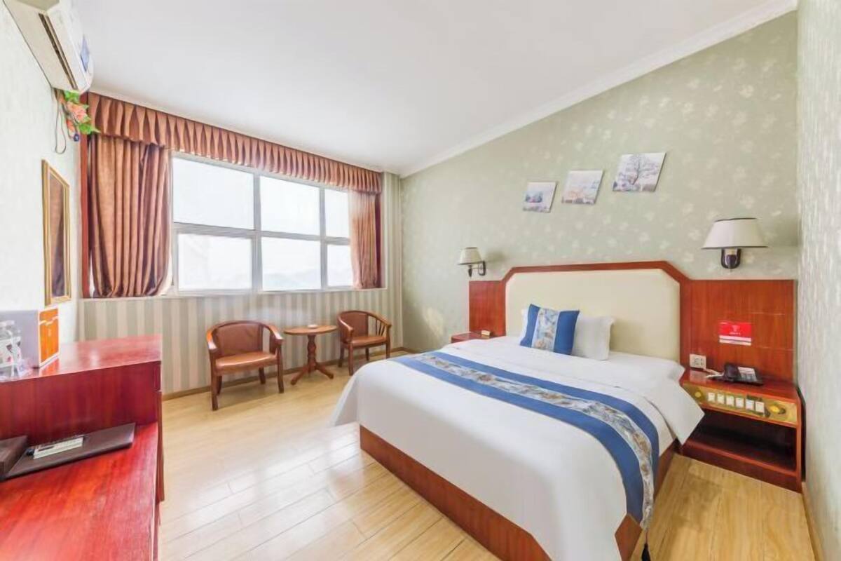Une chambre d’hôtel avec un lit, un bureau, des chaises et une fenêtre.