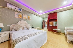 Ein Schlafzimmer mit Bett, Nachttischen, einem kleinen runden Tisch und einer Sitzecke mit Stühlen.