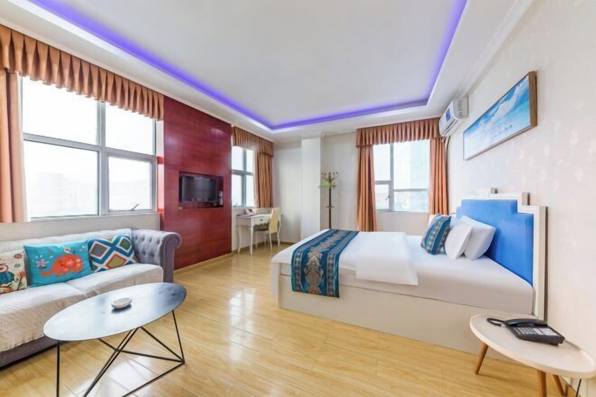 Ein Hotelzimmer mit Sofa, Bett, Schreibtisch und Fernseher.