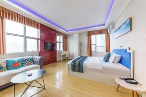 A hotel room with a sofa, a bed, a desk, and a TV. - Junrun Hotel (Guangzhou)