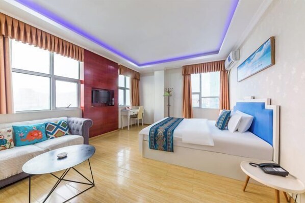 Ein Hotelzimmer mit Sofa, Bett, Schreibtisch und Fernseher.