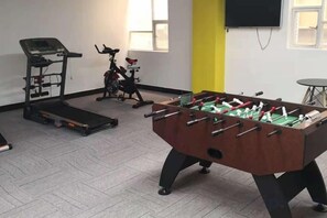 Une pièce équipée d’un baby-foot, d’un tapis de course et de vélos d’appartement.