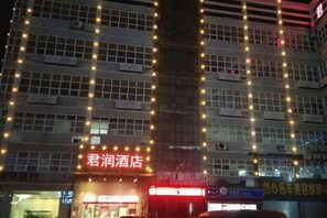 A hotel with multiple floors, a prominent entrance with illuminated signage, and a vertical light string decoration. - Junrun Hotel (Guangzhou)