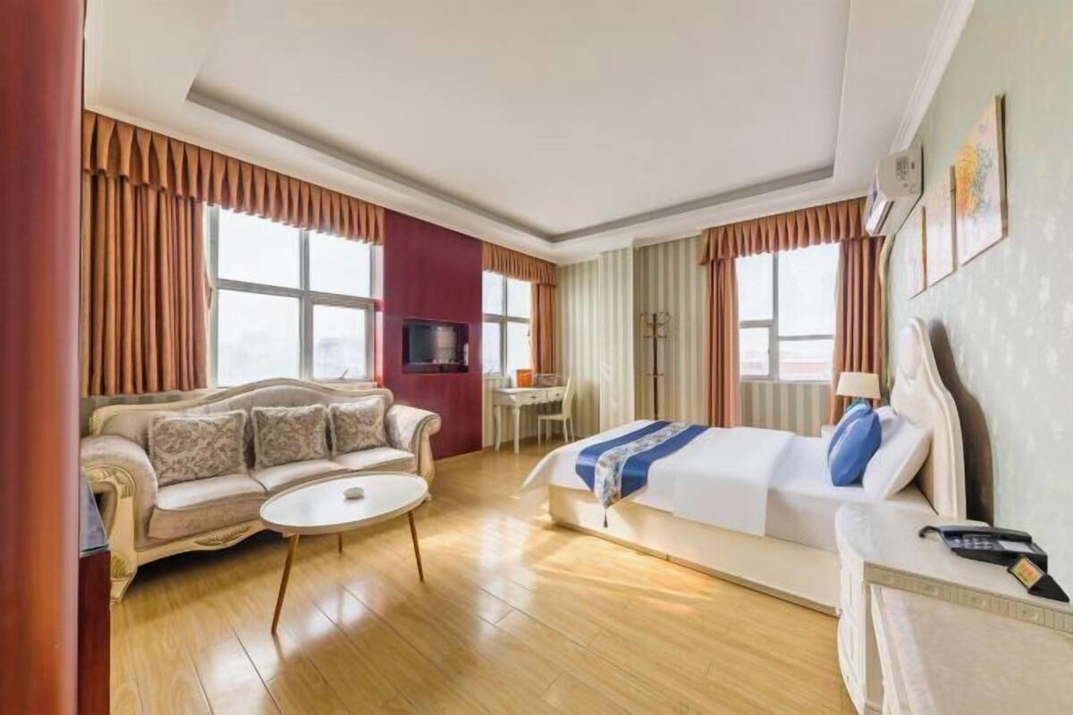 Une chambre d’hôtel avec un canapé, un lit, un bureau et une télévision.