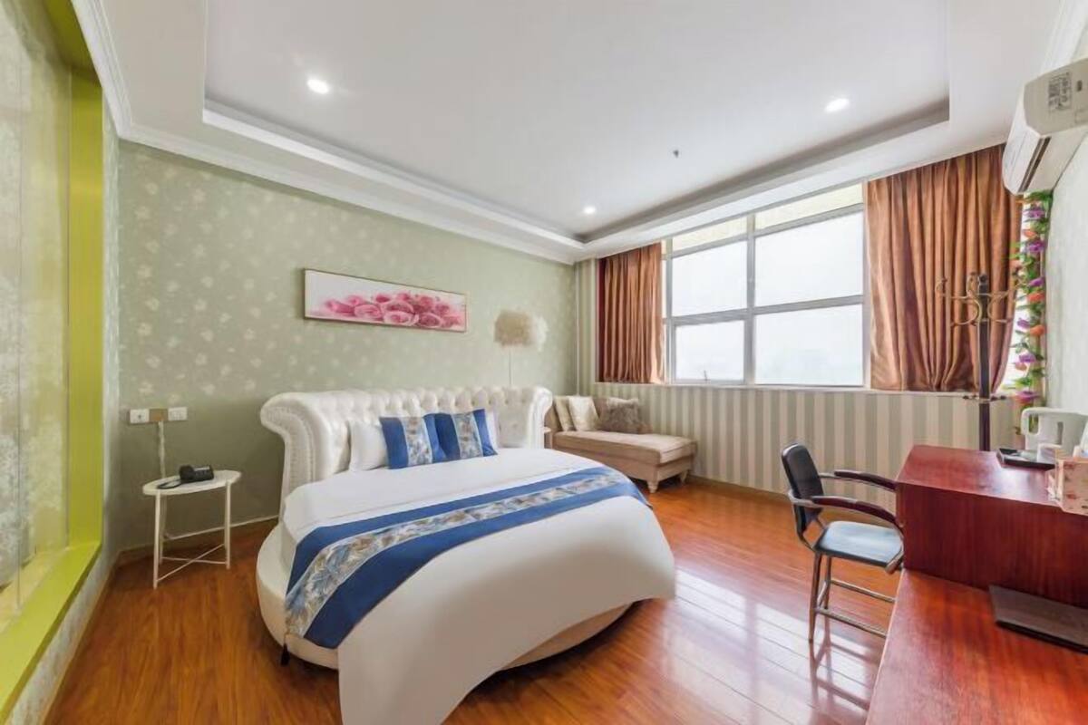 Une chambre à coucher comprenant un lit, un bureau, une chaise, une fenêtre avec des rideaux et un radiateur.