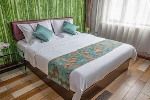 Una cama bien tendida con una colcha floral, un cabecero y dos almohadas.