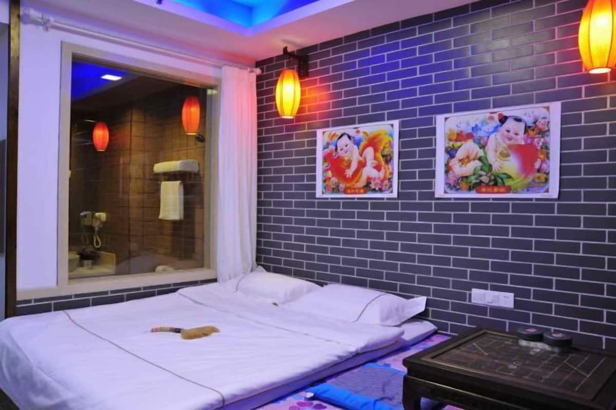 Une pièce comprenant un lit, une table de massage, une fenêtre avec des rideaux et deux lanternes fixées au mur.