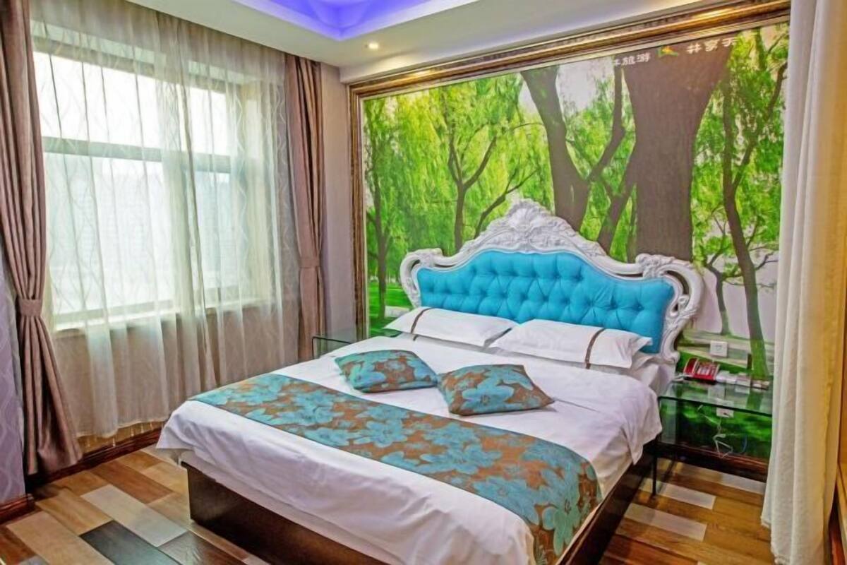 Une chambre avec un grand lit, une fenêtre ornée de rideaux légers et une fresque représentant une forêt sur le mur.