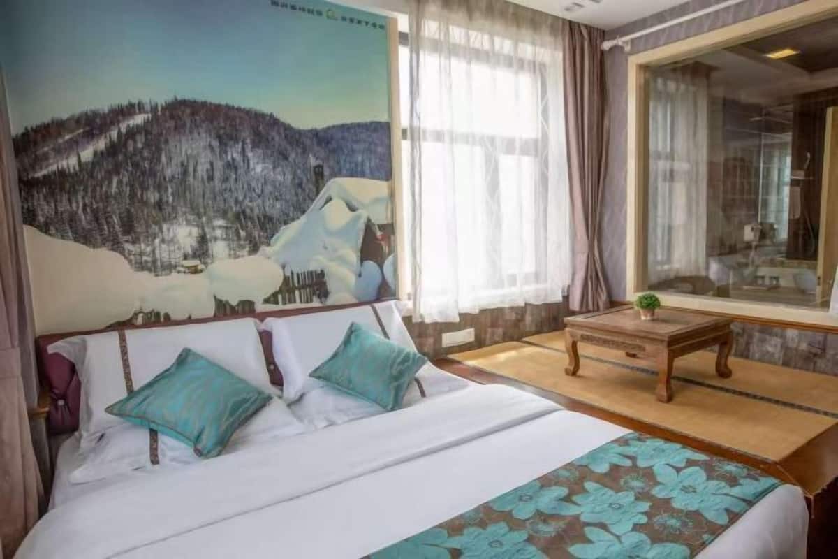 Une chambre à coucher avec un lit, une fenêtre avec des rideaux, une petite table et un tableau accroché au mur.