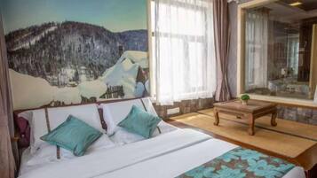 Una camera da letto con un letto, una finestra con tende, un tavolino e un quadro appeso al muro.