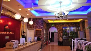 A hotel lobby with a reception desk, a chandelier, and a stone wall.