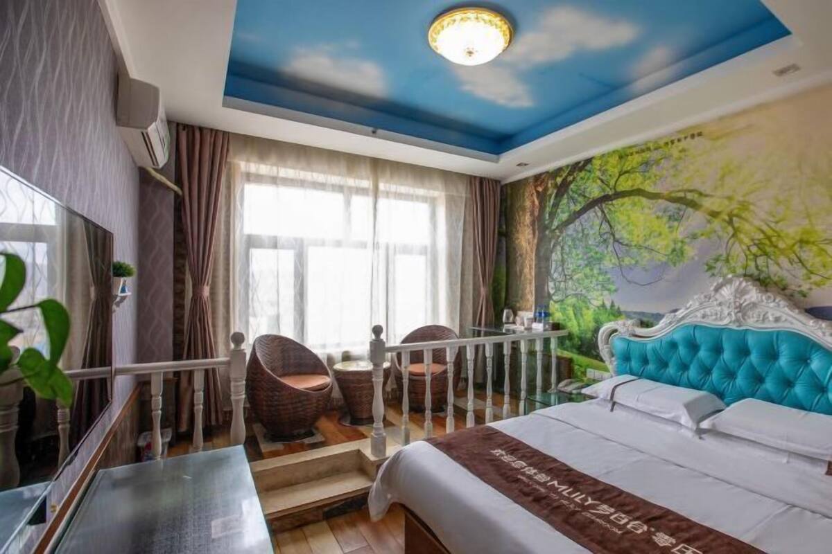Une chambre d’hôtel avec un lit, un balcon, un escalier et une fresque murale.