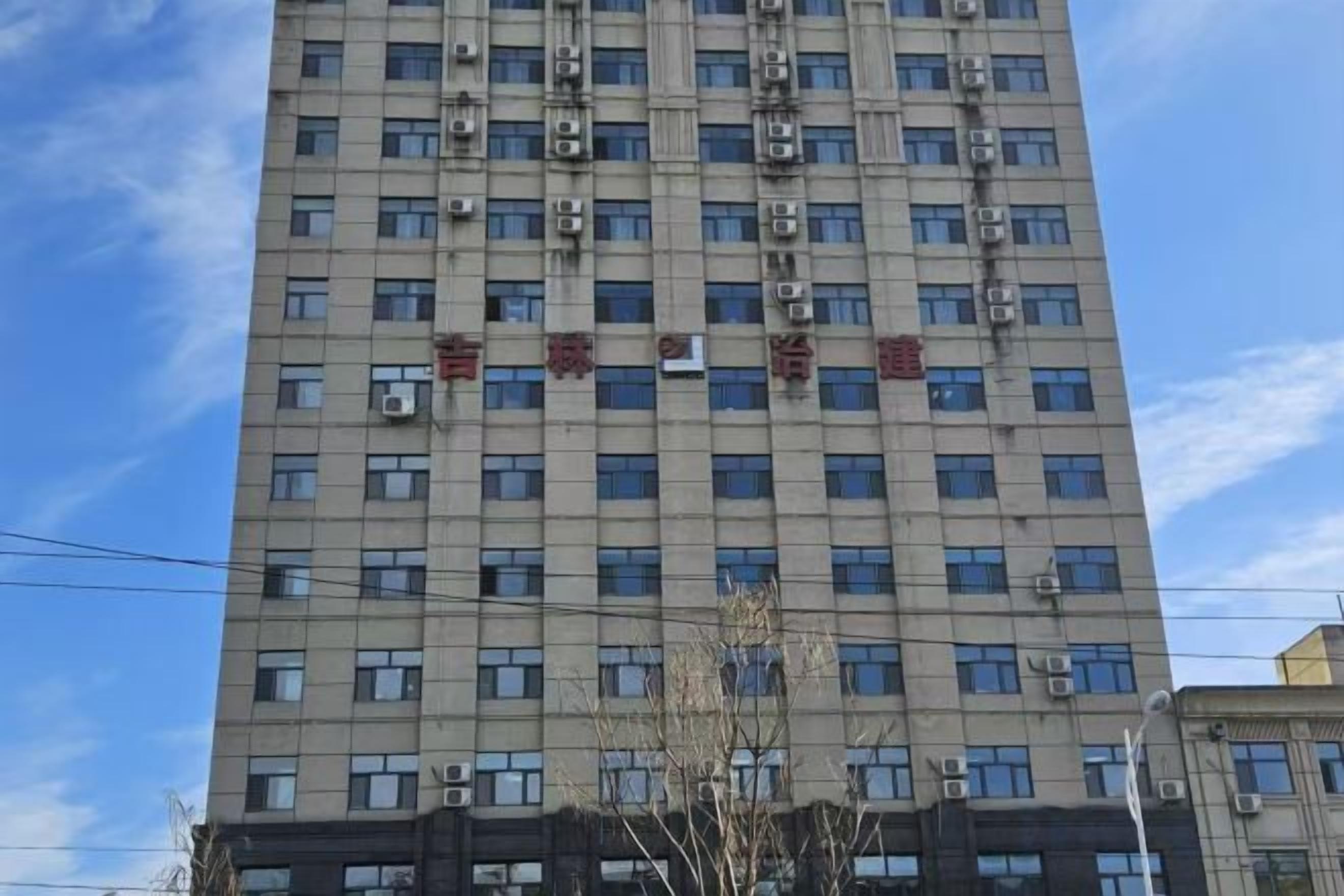 Un edificio de varios pisos con una rejilla de ventanas y unidades de aire acondicionado.