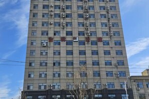 A multi-story building with a grid of windows and air conditioning units. - Sunshine 100 Holiday Hotel (Changyi District Government Branch, Zhongxing Street, Jilin) (Jilin City)