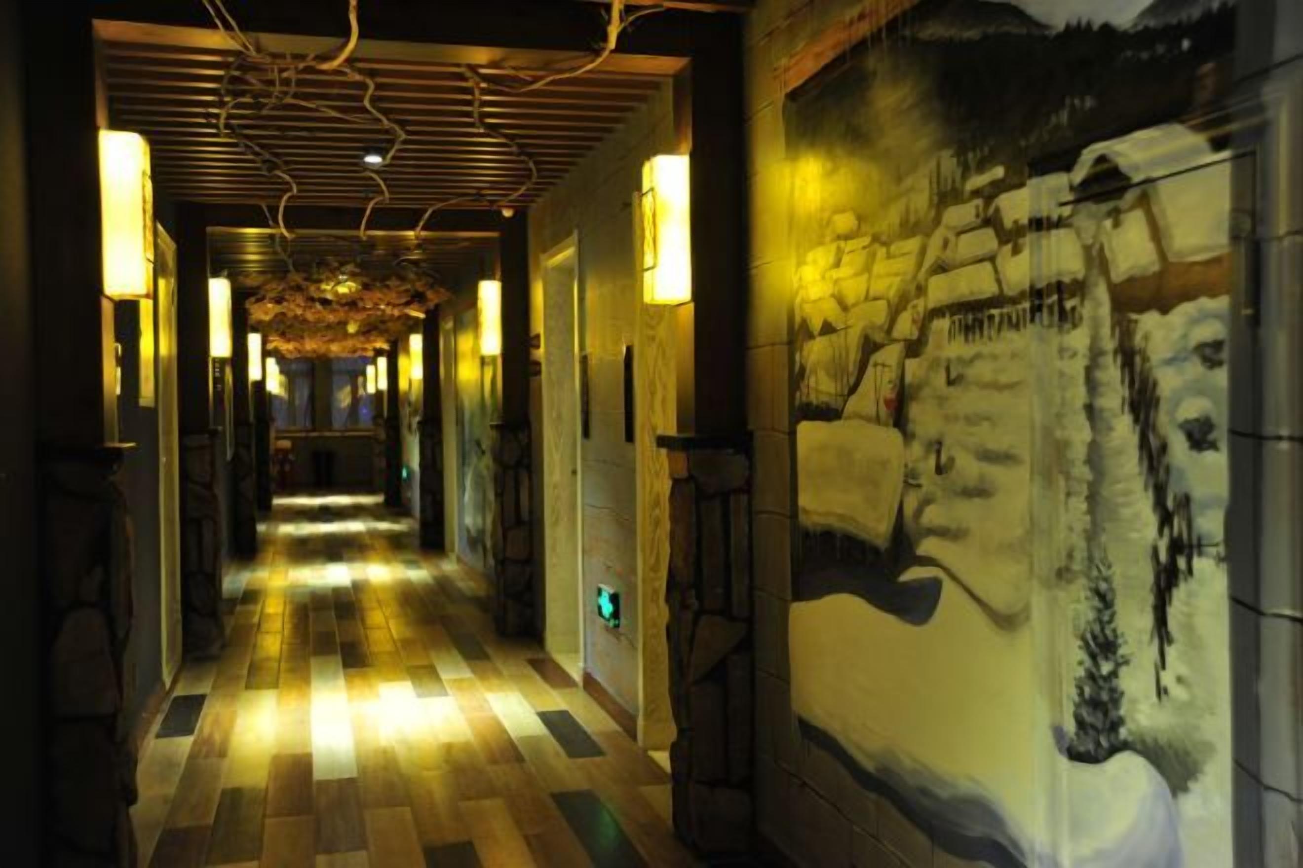 A corridor with a checkered floor, wall-mounted lights, and a mural of a snowy landscape.