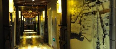 A corridor with a checkered floor, wall-mounted lights, and a mural of a snowy landscape.