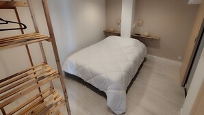 Une chambre avec un lit superposé, une étagère en bois et une table de chevet avec une lampe.