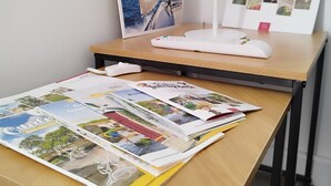 Un bureau avec une lampe, une brochure et une affiche accrochée au mur.