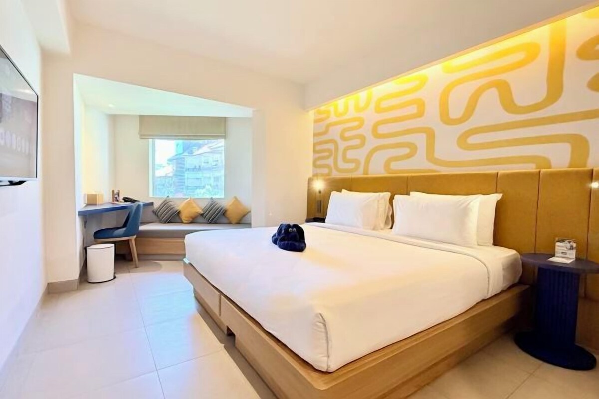 A hotel room with a large bed, a desk, and a view of the outside.